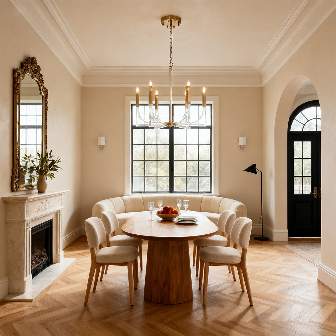 Elegant acrylic chandeliers with six candle-style lights and a polished brass finish, suspended in a warm, sophisticated dining room.