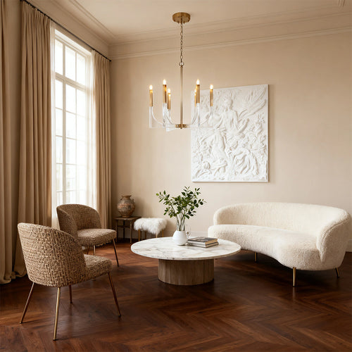 Modern transitional acrylic chandeliers with a brass frame and clear block accents, illuminating a stylish living room with textured furniture.