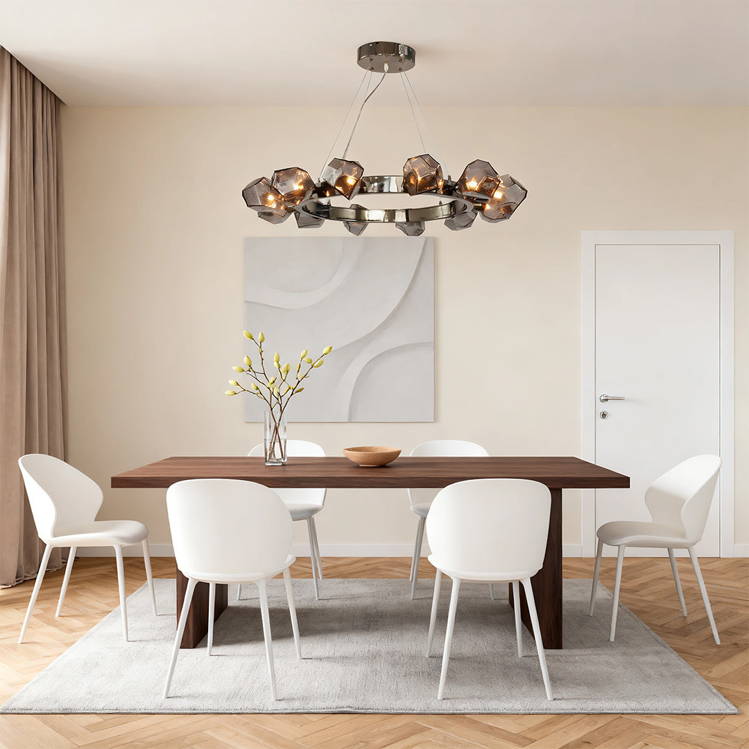 Modern black round chandelier with unique glass petals, centered above a light wood dining table and white chairs in a minimalist room.