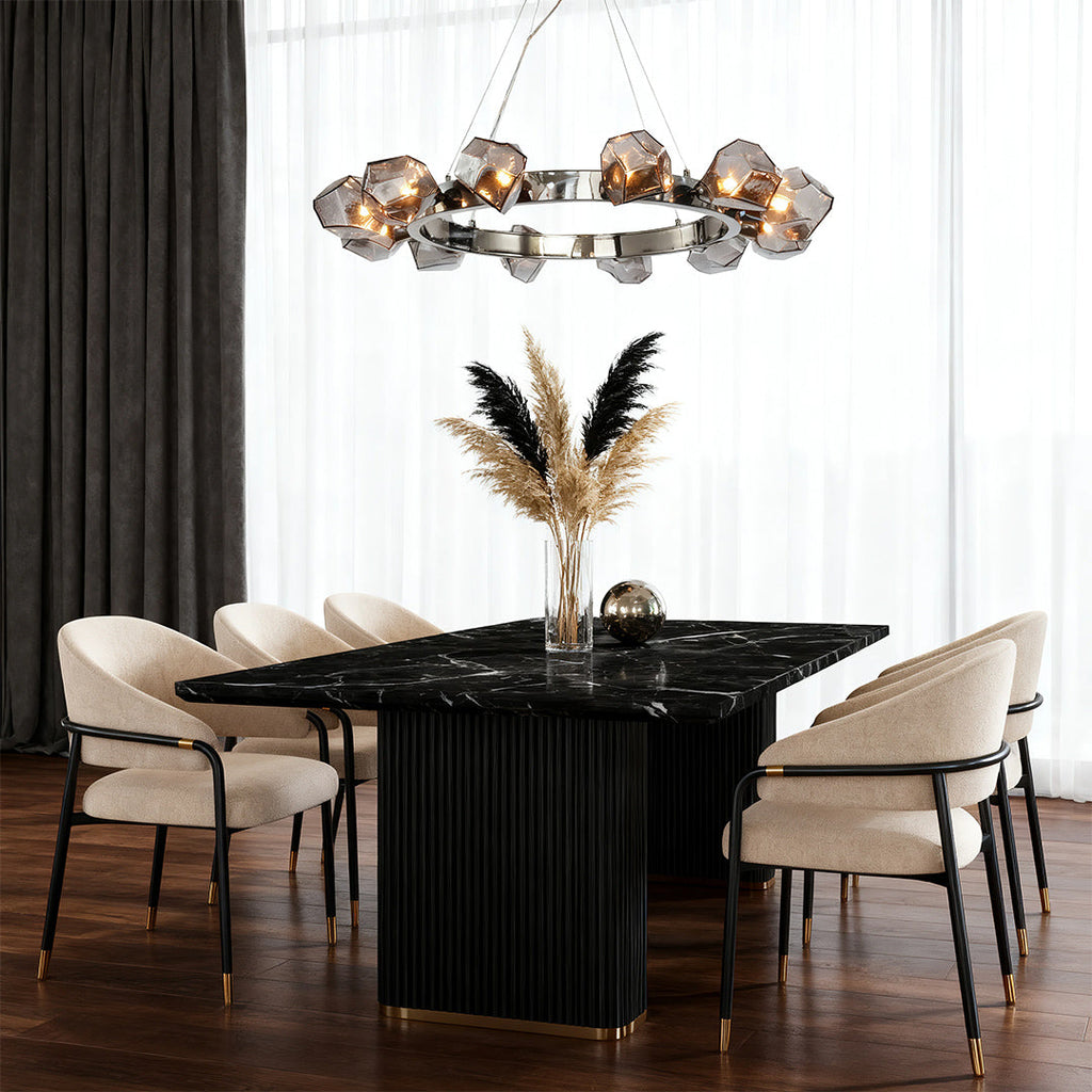 Statement black round chandelier illuminating a dramatic dining setting with a fluted black table, dark curtains, and plush seating.